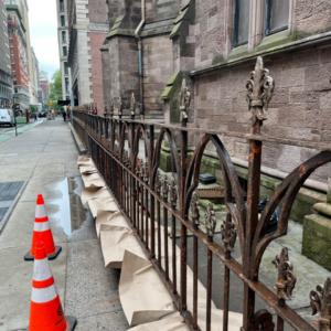 Sanding the Rusted Fence Around the Church
