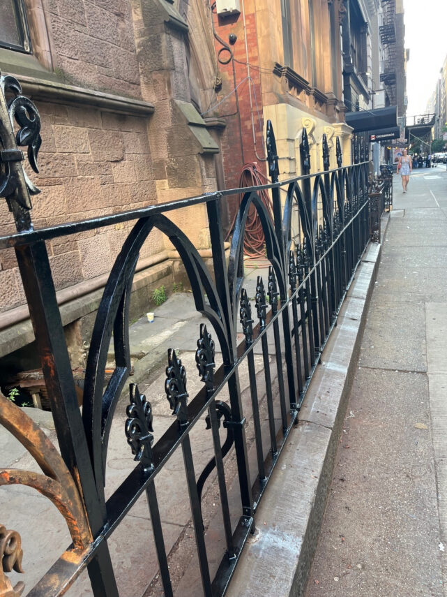 Sanding the Rusted Fence Around the Church